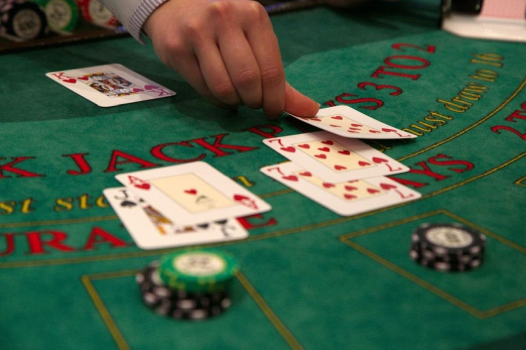dealer plasand al treilea septar pe o masa de blackjack cu jetoane si alte carti intr-un casino