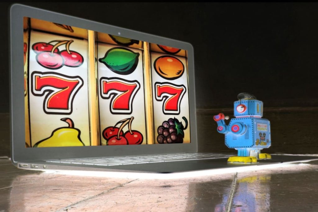 robotel in fata unui lapton pe care este afisat un slot online